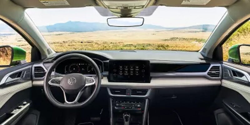 View from inside a car's cockpit showing the steering wheel, dashboard, infotainment screen
