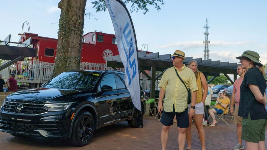 Burlington 4th Fridays concert goers stand next to a Volkswagen from Flow Volkswagen of Burlington